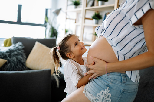 Beautiful pregnant woman with cute child, daughter. Pregnancy, family, love concept.