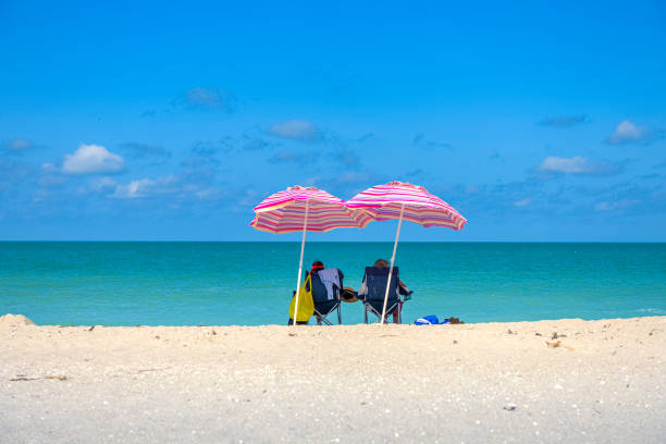 Same-sex couple walking on the beach. They are kissing by the seaSame-sex couple walking on the beach. They are walking, holding hands, kissing, laughing…