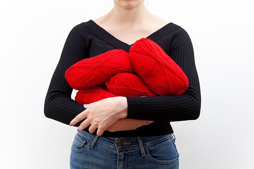 Young woman with an armful of red balls of wool