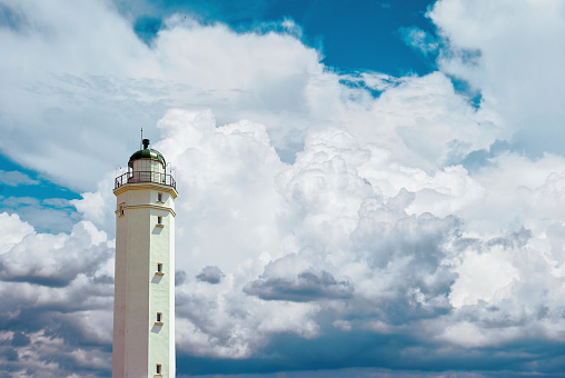 Abstract lighthouse at the seashore with cloudy blue sky