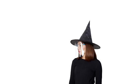 Young asian woman wearing witch costume and face shield for Halloween party
