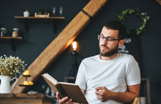istock Young caucasian bearded man reading a book in the kitchen. Home leisure. 1267122825
