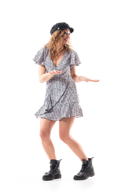 Relaxed young beautiful woman in dress and cap dancing twist and enjoying music Relaxed young beautiful woman in dress and cap dancing twist and enjoying music. Full body length isolated on white background. the twist stock pictures, royalty-free photos & images