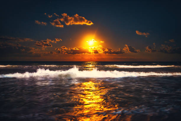 Full moon rising over sea waves. Dramatic sunset over beach.