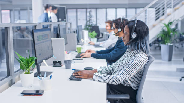 Team of Handsome and Beautiful Diverse Multicultural Customer Service Operators Working at a Busy Modern Call Center with Specialists Wearing Headsets and Actively Taking Calls. Team of Handsome and Beautiful Diverse Multicultural Customer Service Operators Working at a Busy Modern Call Center with Specialists Wearing Headsets and Actively Taking Calls. call center stock pictures, royalty-free photos & images