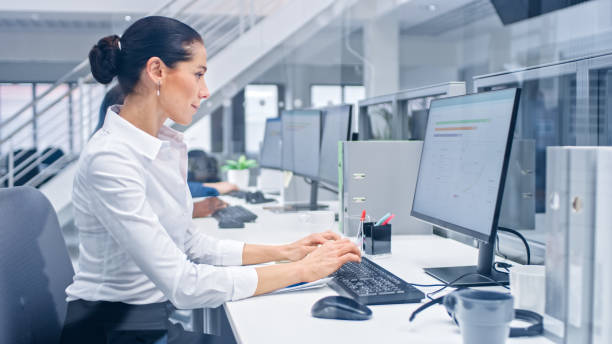 istock Young Handsome Female Manager is Working on Her Personal Computer with Data Statistics, Charts and Graphs. Diverse and Motivated Business People Work in Bright Modern Open Office. 1267134479