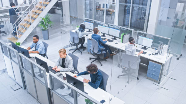 istock Diverse Multinational Team of Business Managers and Specialists Work on Desktop Computers, Have Discussion with Colleagues. Young and Motivated Business People in Modern Open Office. Shot from Above. 1267134503