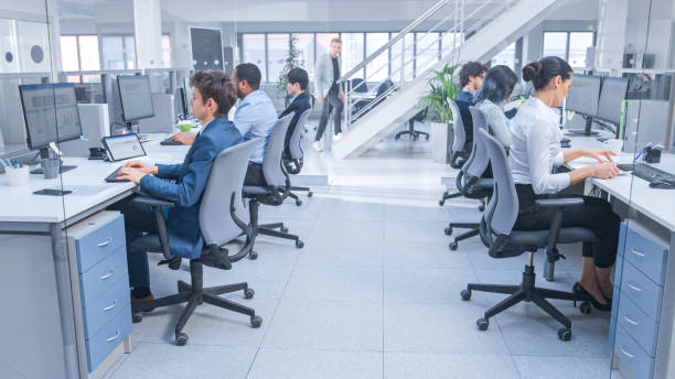 istock Diverse Team of Business Managers and Specialists Work on Desktop Computers with Two Rows of Tables Side by Side. Young and Motivated Business people in Modern Open Office. 1267134521