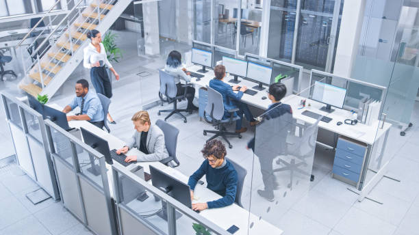 istock Diverse Multinational Team of Business Managers and Specialists Work on Desktop Computers, Have Discussion with Colleagues. Young and Motivated Business People in Modern Open Office. Shot from Above. 1267134538