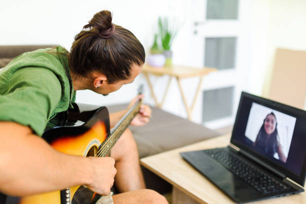 istock Young caucasian man playing the guitar in front of the computer during an online conversation.  / Online music lesson concept. 1267135599