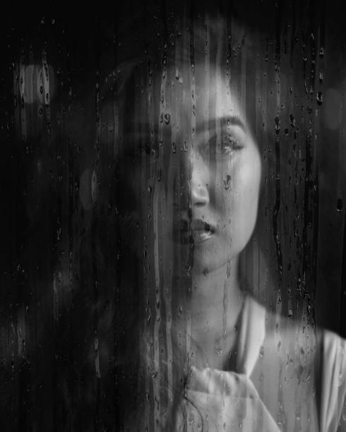 istock Woman Looks From Behind Window 1267139749