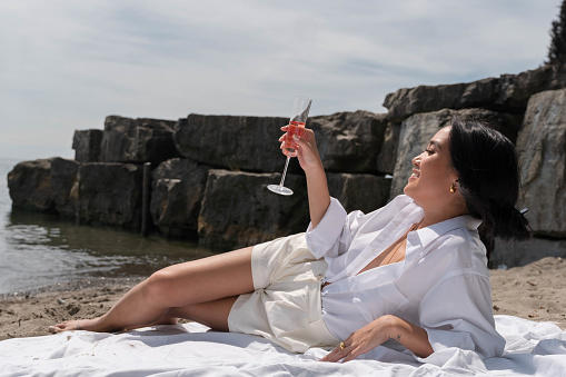 Asian woman lies on the beach and enjoys a cocktail.