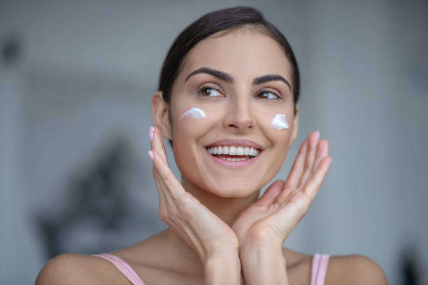 istock Smiling woman applying cream to her cheeks 1267152696