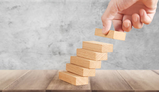 istock Hand liken person stepping up wood block stacking as step stair 1267154681