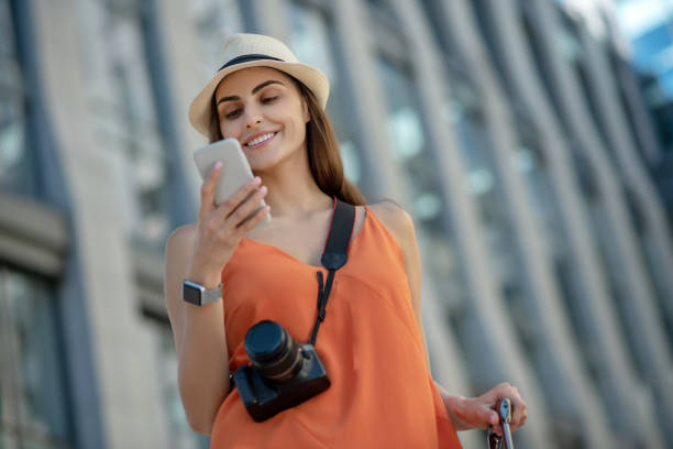istock Dark-haired young woman in a hat holding smartphone and reading 1267156777