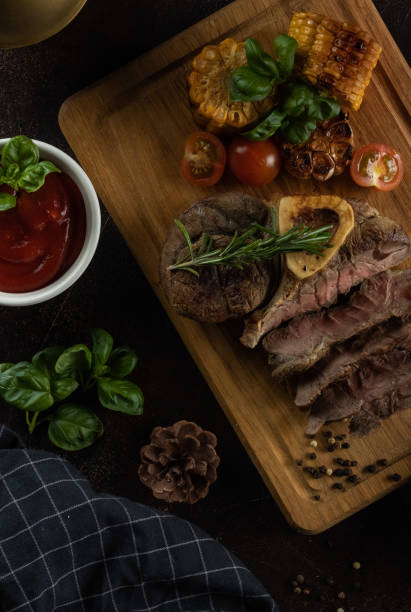 istock Beef steak on the bone with rosemary garlic and cherry tomatoes on a dark background 1267160729