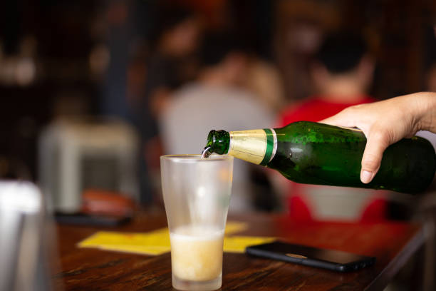 istock Hand pouring beer from bottle into a glass in blur background. 1267161433