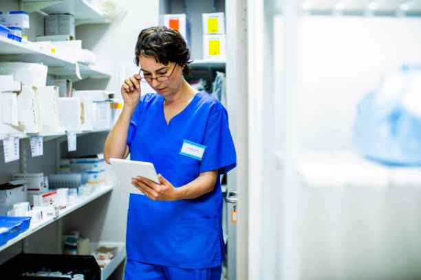 joven doctora haciendo un inventario en un armario del hospital usando una tableta - pharmacy medicine pharmacist storage room fotografías e imágenes de stock