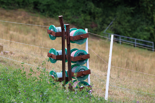 A pair of wooden fence posts are held in a relational position to one another by a horizontal steel fence post and some diagonally placed twisted steel wire.