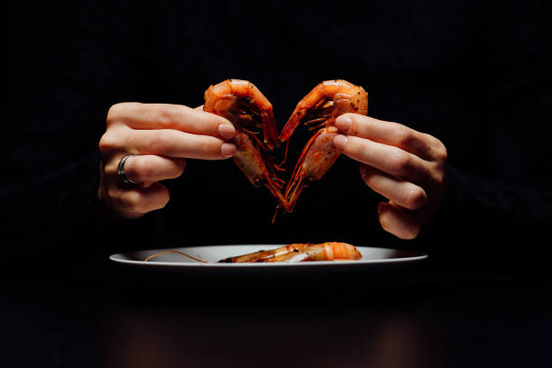 fried shrimps on a black background fried heart shaped shrimp in woman's hands on black background black tiger shrimp stock pictures, royalty-free photos & images