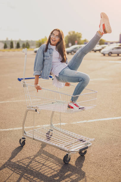 istock Excited young lady having fun on shopping trolley 1267165221