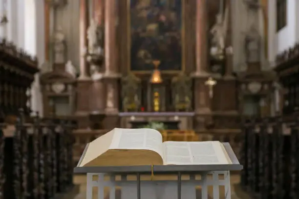 Photo of Bible or prayer book lying on praying bench in catholic church, selective focus