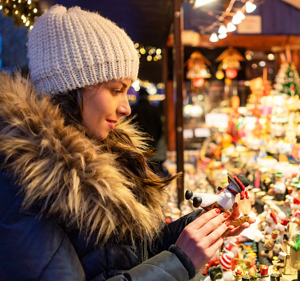 A woman choosing a gift to buy at a winter market stall.