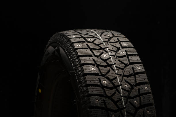 istock studded winter tire, side view. Close-up on a black background 1267167559
