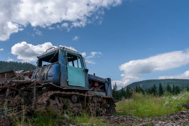 istock an old abandoned crawler tractor in a field against a cloudy sky, forest and mountains 1267167636