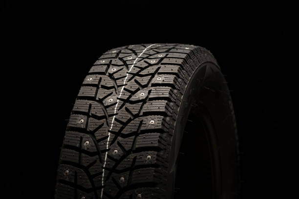 istock studded winter tire, side view. Close-up on a black background 1267168535