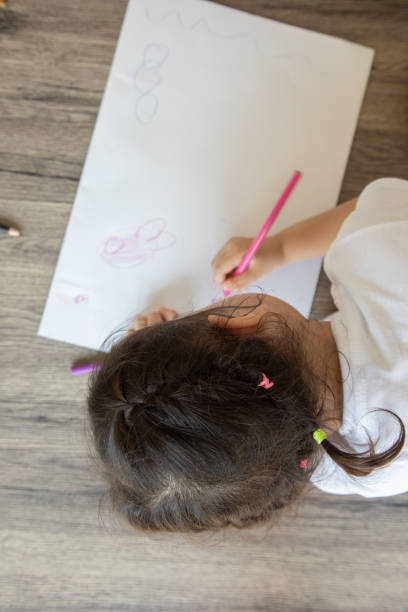 istock Photos from above and selective focus with blurred background for colorful drawing by color pencils on white paper placed on a wooden table by preschoolers for learning to develop creativity and enjoyment. 1267168849