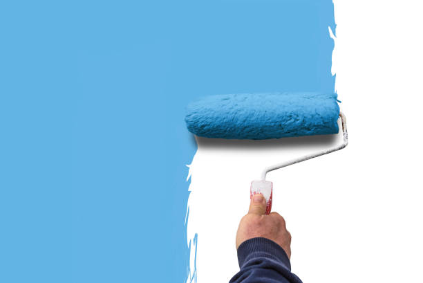 istock hand holds paint roller and painting a wall 1267168930
