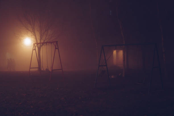 Swings in the fog at night with silhouettes in the distance, Belgrade, Serbia the most polluted town in Europe.