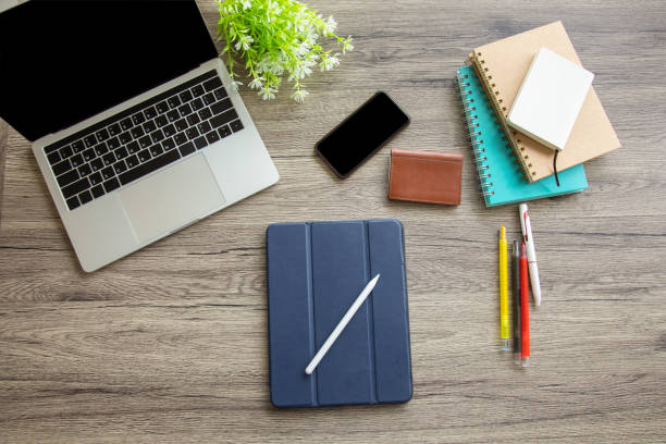 istock A top view of a business desk with tablet includes a multi-colored pens, notebook, business card bag, computer laptop and smartphone on a wooden table to connect with others in the digital technology world with copy space. 1267171832