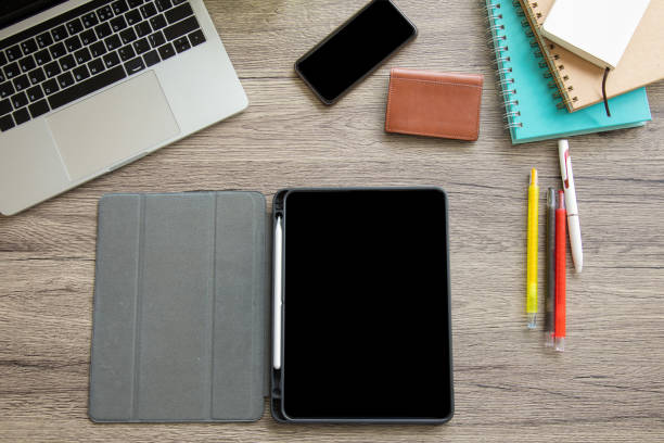 istock A top view of a business desk with opening tablet includes a multi-colored pens, notebook, business card bag, computer laptop and smartphone on a wooden table to connect with others in the digital technology world with copy space. 1267172069