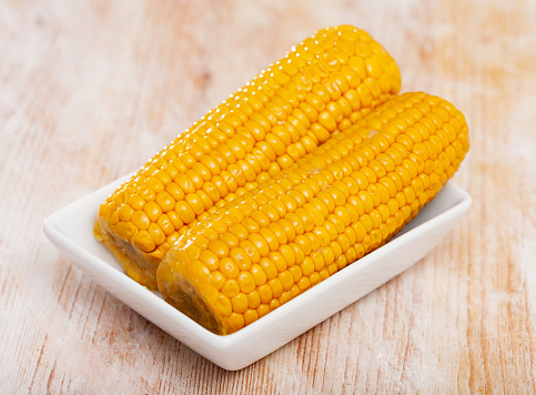 Closeup view of the homemade golden corn cobs on plate. Delicious and healthy food closeup