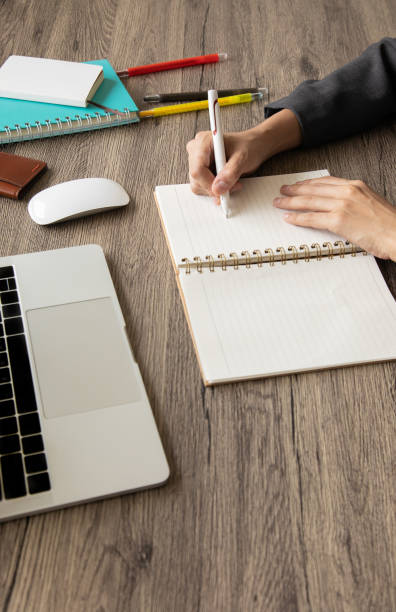 istock A side view with selective focus of a business desk with hand writing on notebook with computer laptop and color pens  on a wooden table to connect with others in the digital technology world. 1267172165