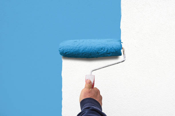 istock hand holds paint roller and painting a wall 1267174285