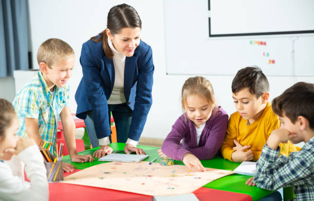 istock Teacher and happy schoolkids playing board game 1267174808