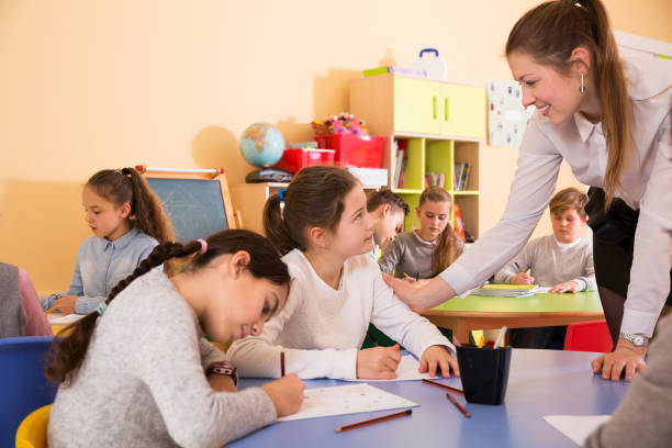 istock Teacher helping children drawing 1267174844