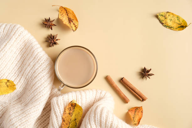 istock Autumn flat lay composition with white knitted scarf, coffee cup, cinnamon sticks, fallen leaves on beige background. Cozy home desk, hygge style. 1267175465