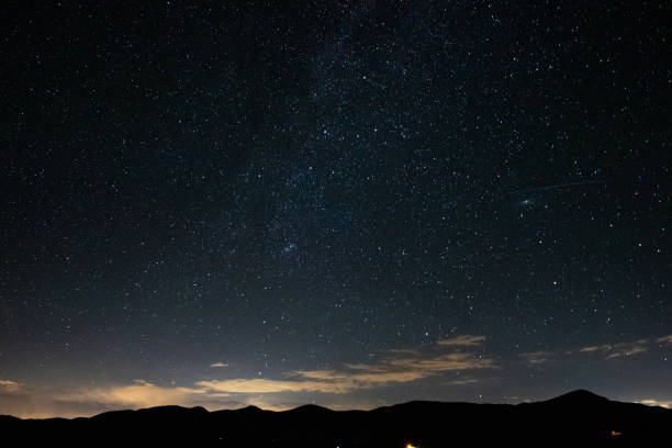 istock Stars and clouds over the mountains at night 1267176943