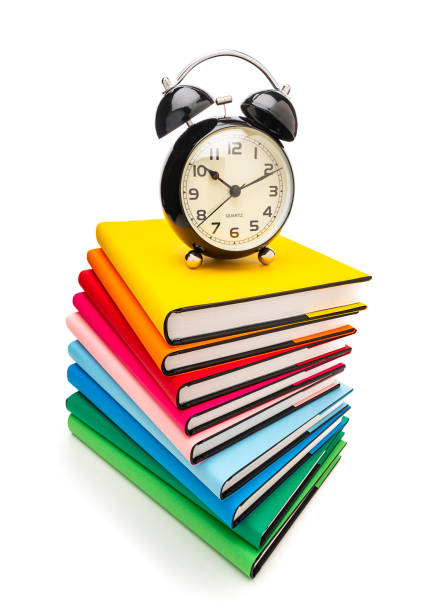 istock Stack of multicolored books and alarm clock isolated on white background 1267177990