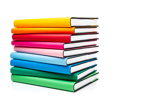 Front view of rainbow colored books arranged in a stack isolated on white background. The composition is at the left of an horizontal frame leaving useful copy space for text and/or logo at the right.High resolution 42Mp studio digital capture taken with SONY A7rII and Zeiss Batis 40mm F2.0 CF lens