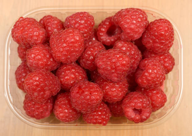 istock large ripe raspberries in a transparent plastic container 1267179332