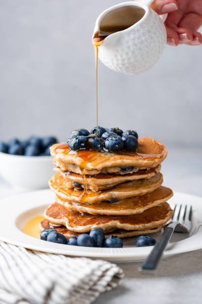 Syrup pouring on pancakes Syrup pouring on pancakes. Pancakes with blueberries and sweet syrup honey jar liquid gourmet stock pictures, royalty-free photos & images