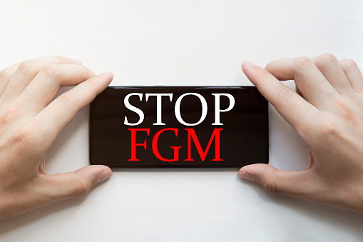 male hands are holding black phone with text Stop Fgm on white background