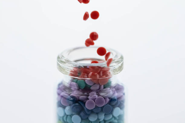 istock Colorful multicolor beads or tablets are poured into a glass bottle. A rainbow in a bottle. Magic pills. 1267181274