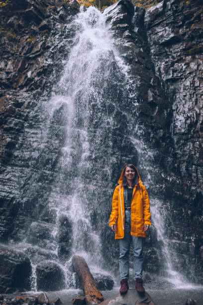 istock woman in yellow raincoat at autumn waterfall 1267181719
