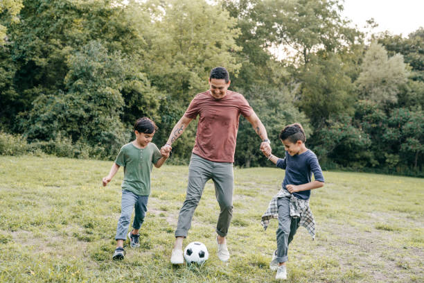 istock Hispanic dad playing soccer with sons 1267182531